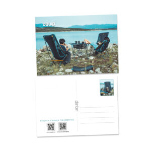 Postkarte mit uquip Leichtgewicht-Stühlen am Ufer eines Gewässers in einer Umgebung mit Steinen und Bergen genießen.